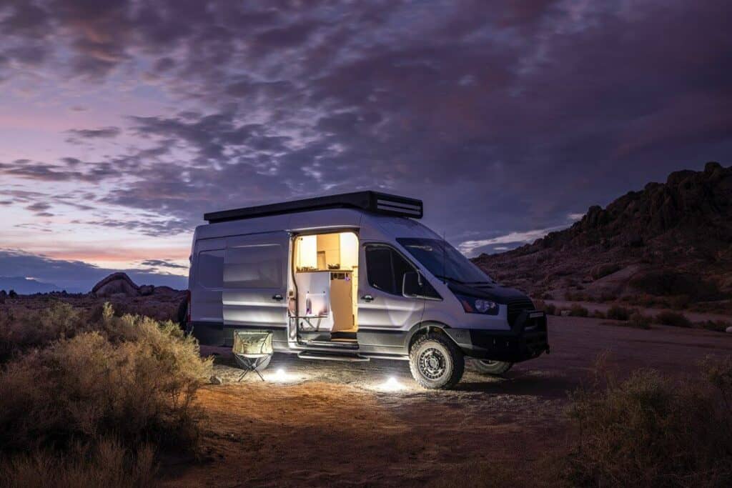 Van Camped At Night With View Inside Of Kitchen