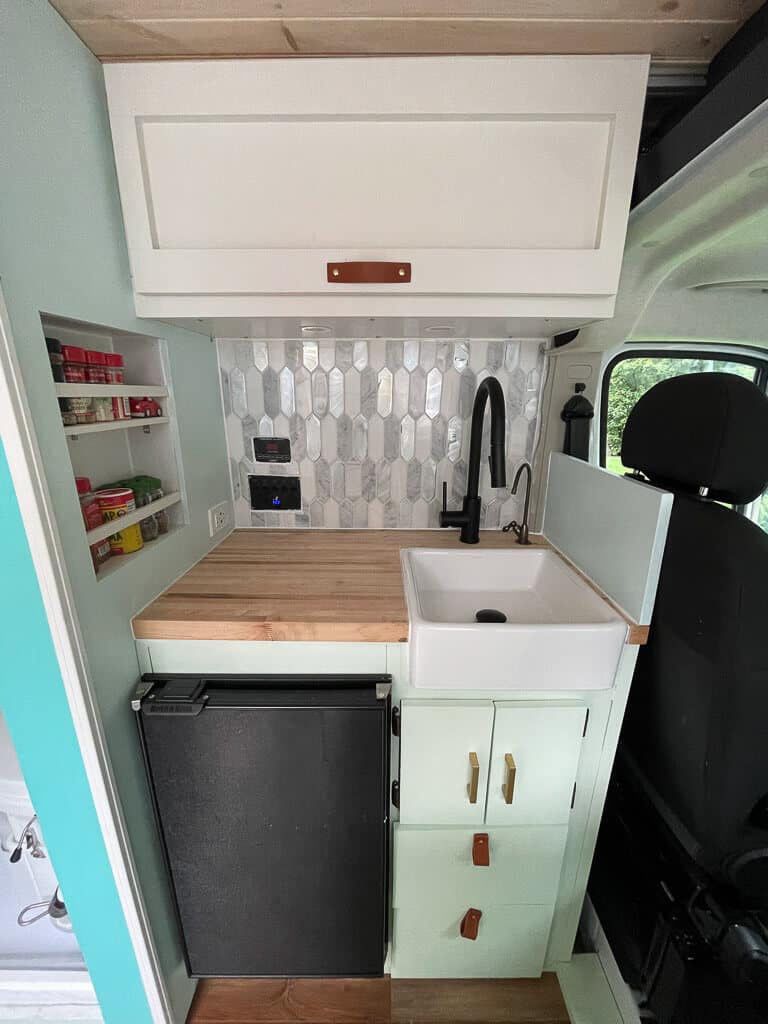 A Campervan Kitchen With Fridge And Sink On The Drivers Side Of A Campervan