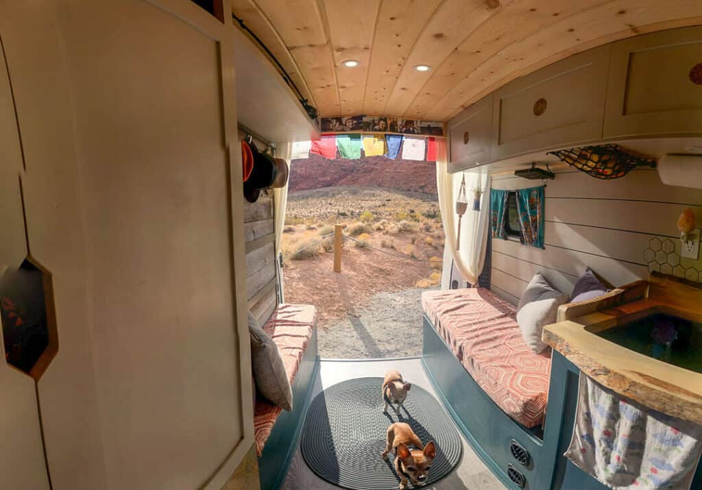 Two Bench Seats With A Murphy Bed Folded Up On The Left Side In A Campervan