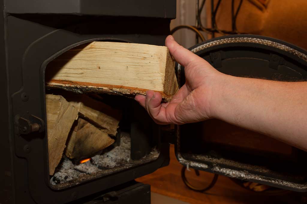 Putting Wood In A Wood Burning Campervan Stove