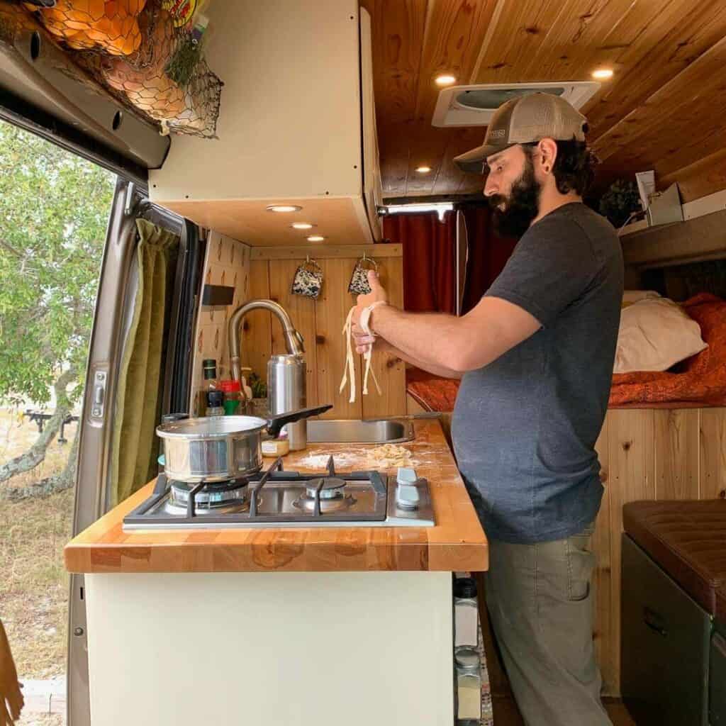 Man Making Pasta In A Campervan Kitchen