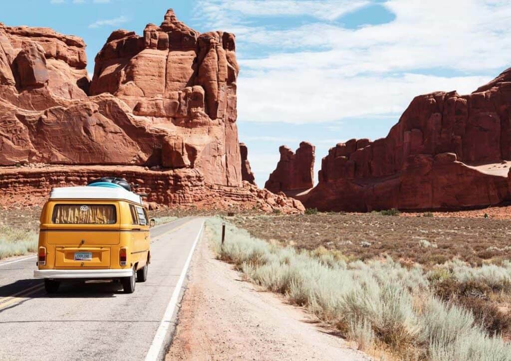 Volkswagon Bus Driving Through Red Rocks