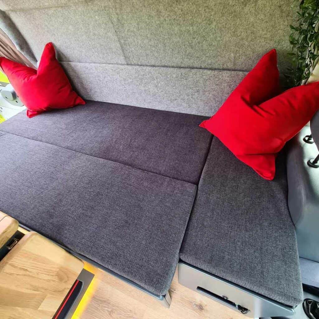 A L-Shaped Futon/Couch That Converts To A Bed In A Campervan